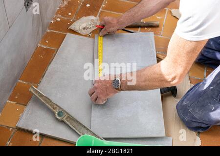 Der fliesenleger Maßnahmen die Fliesen vor dem Schneiden Stockfoto