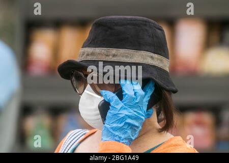 Beirut, Libanon. 20. April 2020. Eine Frau, die während der Coronavirus-Pandemie eine chirurgische Maske und Handschuhe gegen Covid-19-Infektionen trägt, während sie ein Mobiltelefon hält. Der Libanon bleibt bis zum 26. April 2020 in der Blockierung, da die Regierung die Bürger dringend aufgefordert hat, zu Hause zu bleiben und nur für wichtige Geschäfte zu gehen. Kredit: amer Ghazzal/Alamy Live News Stockfoto