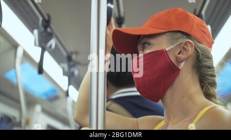 Frau fährt kaukasische Fahrt im überirdischen Zug airtrain mit Schutzmaske. Mädchen Tourist im airtrain mit Atemschutzmaske. Personenmaske. Stockfoto