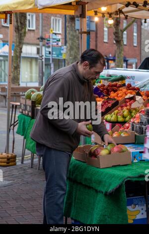 Ein Lebensmittelhändler, der auf seinem Obst- und Gemüsestall oder Marktstand Vorrat legt Stockfoto