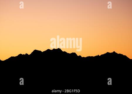 Orange Sonne versinkt hinter den Bergen Stockfoto