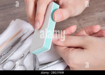 Eine Frau poliert ihre Nägel. Feilen Sie Ihre Nägel. Maniküre, Nagelhaut, Hygiene, Verfahren. Handpflege, Hausmaniküre. Nagelstudio, Spa, Schönheit. Stockfoto