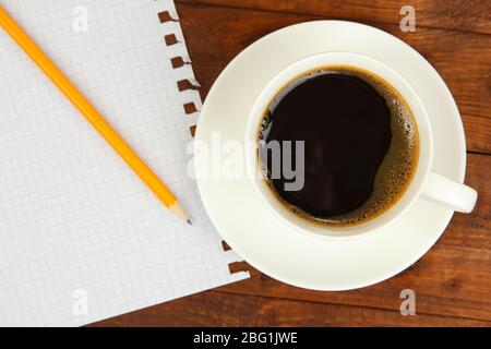 Tasse Kaffee auf dem Arbeitstisch, der mit Dokumenten aus nächster Nähe bedeckt ist Stockfoto