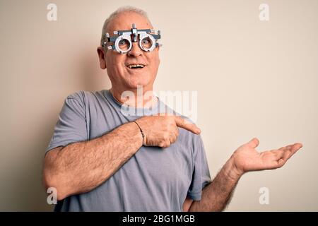 Mittelalter Hoary Mann Kontrolle Vision trägt Optometrie Brille über weißem Hintergrund erstaunt und lächelnd auf die Kamera, während mit der Hand ein präsentieren Stockfoto