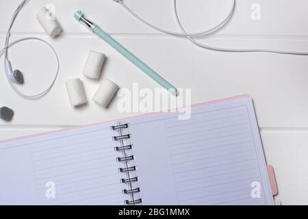 Tagesplaner auf weißem Holzhintergrund. Nahaufnahme, Kopierbereich, Freiraum, Mockup. Sauberes Blatt, flaches Lay, Draufsicht. Notizblock, Stift, Kopfhörer, to-d Stockfoto