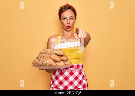 Mittelalter Senior Hausfrau Pin up Frau trägt Stil 50er Jahre Retro-Kleid Kochen Vollkorn Brot zeigen mit Finger auf die Kamera und zu Ihnen, Hand SIG Stockfoto