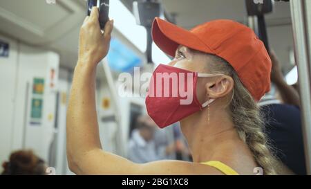 Frau fährt kaukasische Fahrt im überirdischen Zug airtrain mit Schutzmaske. Mädchen Tourist im airtrain mit Atemschutzmaske. Personenmaske. Stockfoto