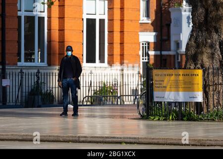Ein Mann mit einer Gesichtsmaske steht auf dem Windrush Square, Brixton, während der Londoner Sperrung aufgrund der Verbreitung von Covid-19, 19. April 2020 Stockfoto