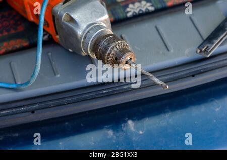 Alte elektrische Bohrmaschine mit Bohrer. Veraltete elektrische Bohrmaschine mit rostigen Nockenaufnahme. Zuverlässiges Elektrowerkzeug. Industriethemen. Nahaufnahme. Selektiver Fokus. Stockfoto