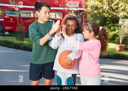 Multikulturelle Schüler in der Grundschule beim Sport geben High Five Motivation Stockfoto