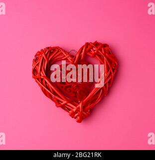 Rotes Weidenkorb-Deko-Herz auf rosa Hintergrund, festliche Kulisse, Draufsicht Stockfoto