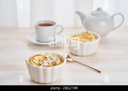 Apfelkuchen und eine Tasse Tee auf weißem Holztisch in der Küche. Stockfoto