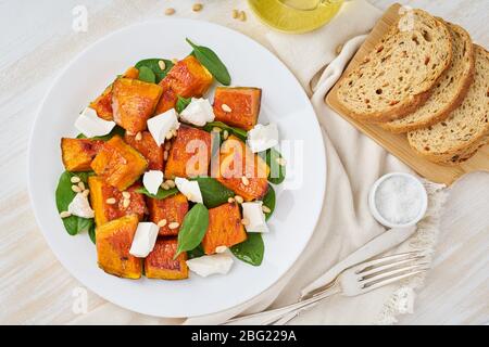 Salat mit geröstetem Kürbis, Fetakäse, Spinat, Nüssen mit Honig und Gewürzen, Draufsicht Stockfoto