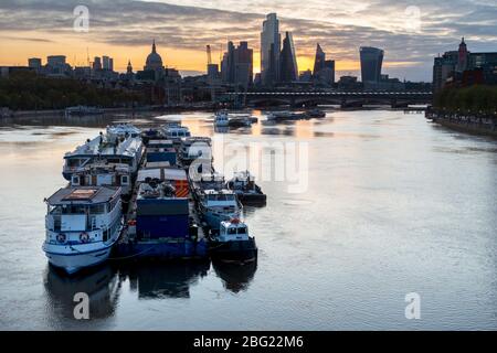 Am frühen Morgen werden leichte Vergnügungsboote auf der Themse mit St Paul's und der City of London im Hintergrund vertäut. Von der Waterloo Bridge Stockfoto