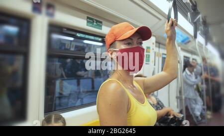 Frau fährt kaukasische Fahrt im überirdischen Zug airtrain mit Schutzmaske. Mädchen Tourist im airtrain mit Atemschutzmaske. Personenmaske. Stockfoto