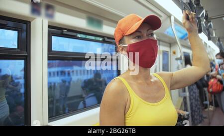 Frau fährt kaukasische Fahrt im überirdischen Zug airtrain mit Schutzmaske. Mädchen Tourist im airtrain mit Atemschutzmaske. Personenmaske. Stockfoto