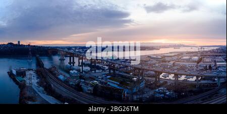 Luftdrohne-Aufnahme des Pendlerverkehrs auf der zweiten Narrows-Brücke und den Industriehafen in Vancouver, BC, Kanada bei Sonnenuntergang. Stockfoto