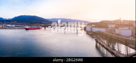 Luftdrohne-Aufnahme des Pendlerverkehrs auf der zweiten Narrows-Brücke und den Industriehafen in Vancouver, BC, Kanada bei Sonnenaufgang. Stockfoto