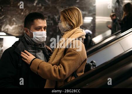 Junger Mann und Frau in medizinischen Masken auf Rolltreppe in der U-Bahn. Stockfoto