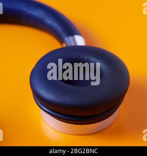 Nahaufnahme eines schwarzen kabellosen Full Size Headphones auf orangefarbenem Hintergrund Stockfoto