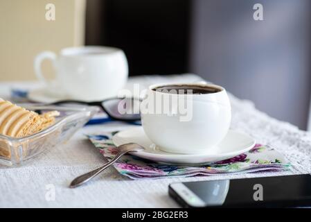 Zwei weiße altmodische Tasse Tee oder Kaffee auf dem Tisch zu Hause. Konzept für den Aufenthalt zu Hause. Stockfoto