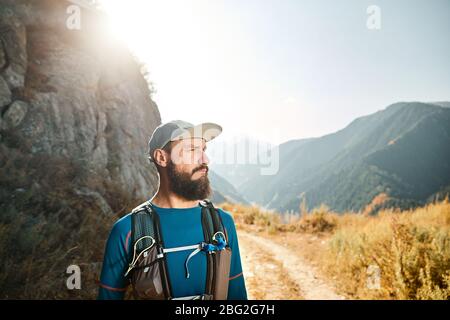 Portrait von bärtigen runner Athlet mit Rucksack in den Bergen bei Sonnenaufgang Stockfoto
