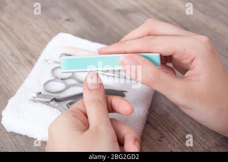 Eine Frau poliert ihre Nägel. Feilen Sie Ihre Nägel. Maniküre, Nagelhaut, Hygiene, Verfahren. Handpflege, Hausmaniküre. Nagelstudio, Spa, Schönheit. Stockfoto