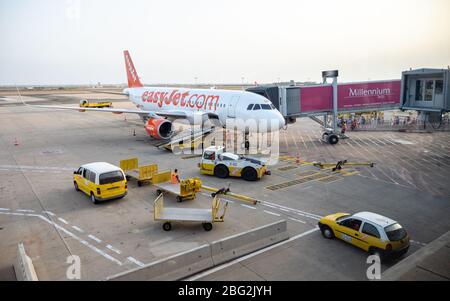Ein easyJet-Flugzeug steht am internationalen Flughafen Faro, Portugal, an einem Gate, und Gepäckabfertiger warten darauf, den Gepäckraum zu entladen.
