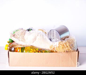 Verschiedene Konserven und Getreide in einer Kartonbox. Lebensmittelspenden. Lieferung von Lebensmitteln Stockfoto