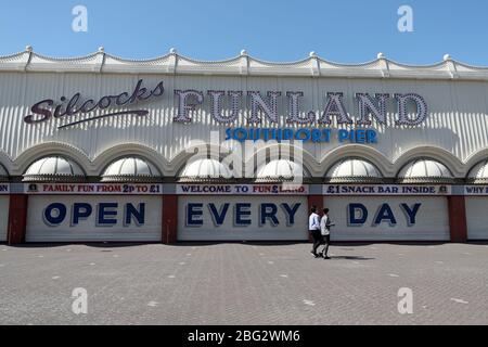 Zwei Personen gehen an den geschlossenen Fensterläden vorbei, mit einem Schild mit der Aufschrift "Open Every Day", am Silcocks Funland und Pier, Southport, während Großbritannien weiterhin gesperrt wird, um die Ausbreitung des Coronavirus einzudämmen. Stockfoto