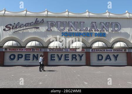 Zwei Personen gehen an den geschlossenen Fensterläden vorbei, mit einem Schild mit der Aufschrift "Open Every Day", am Silcocks Funland und Pier, Southport, während Großbritannien weiterhin gesperrt wird, um die Ausbreitung des Coronavirus einzudämmen. Stockfoto