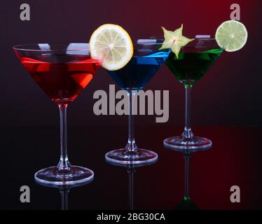 Alkoholische Cocktails in martinigläsern auf dunkelrotem Hintergrund Stockfoto