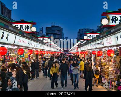 Touristen in der beliebten Nakamise Shopping Street in der Nähe des Senso-ji Temple in Tokio, Japan, aufgenommen in der Abenddämmerung Stockfoto