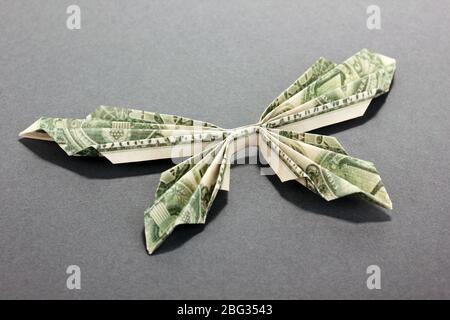 Dollar gefaltet in Schmetterling auf grauem Hintergrund Stockfoto