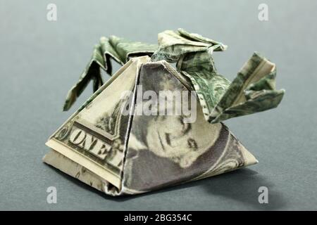 Dollar gefaltet in ägyptische Pyramide auf grauem Hintergrund Stockfoto