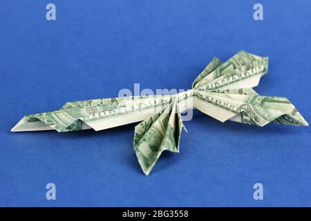 Dollar gefaltet in Schmetterling auf blauem Hintergrund Stockfoto