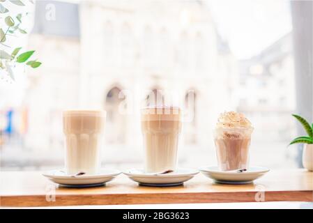 Drei Gläser Kaffeegetränke. Kaffee Latte, Latte mit Schokolade und Kaffee Mokka in der Nähe des Fensters Stockfoto