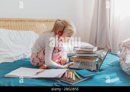 Kaukasische Mädchen Kind im Bett sitzen und online lernen auf Laptop-Internet. Virtuelle Klasse Unterricht Schule auf Video-Chat während der Selbstisolierung Quarantäne Stockfoto