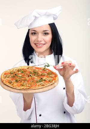 Schöne Mädchen Chef-Herd mit Pizza isoliert auf weiß Stockfoto