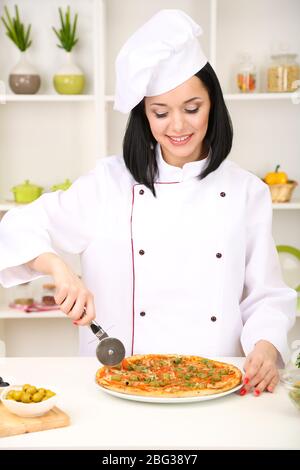 Schöne Mädchen Chef-Herd mit Pizza auf Küche Hintergrund Stockfoto