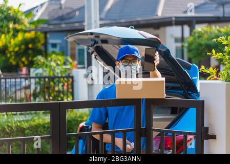 Asiatische Lieferung Mann Kurier Ort Lieferungen Boxen zu Hause und zeigt Handy leeren Bildschirm für Kunden unterzeichnen er Schutzmaske Service unde Stockfoto