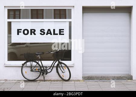 Zum Verkauf Zeichen im Schaufenster mit Fahrrad außerhalb geparkt - Shop Vakanz aufgrund von Geschäftsschluss - Wirtschaftskrise und Rezession Konzept Stockfoto