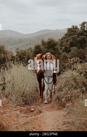 Mädchen, die mit ihrem Pferd durch ländliche Landschaft läuft, Kalifornien, USA Stockfoto