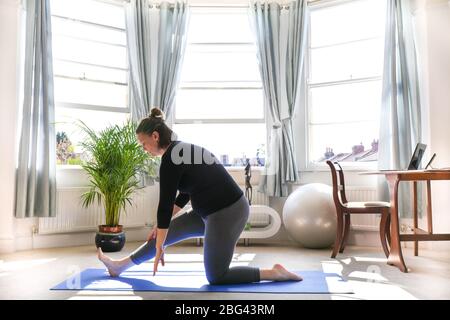 Ganzkörperportrait einer schwangeren Frau auf Yoga-Matte zu Hause. Training, Yoga und Schwangerschaft. Fitness zu Hause Stockfoto