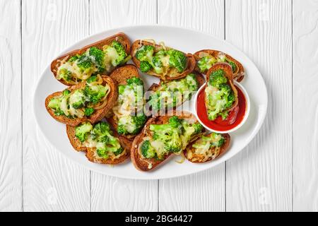 Brokkoli schmilzt offene vegane Sandwiches mit geröstetem Brokkoli auf geröstetem Roggenbrot mit geschmolzenem Provolonkäse auf einem weißen Teller mit Ketchup Stockfoto