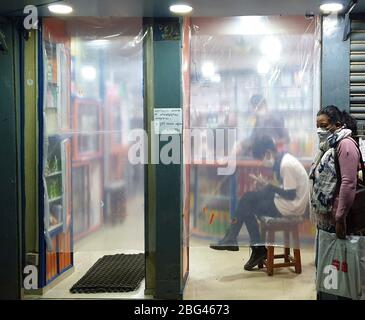 Kathmandu, Nepal. April 2020. Eine Frau wartet vor einer Apotheke mit Plastikfolie, um direkten Kontakt mit Menschen in Kathmandu, Nepal, 20. April 2020 zu vermeiden. Kredit: Sunil Sharma/Xinhua/Alamy Live News Stockfoto