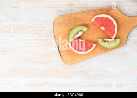 Geschnittenes Obst auf einem Holzbrett und einem weißen blauen Hintergrund mit Copyspace Stockfoto
