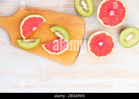 Geschnittenes Obst auf einem Holzbrett und einem weißen blauen Hintergrund mit Copyspace Stockfoto