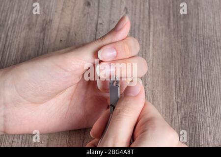 Eine Frau macht eine Maniküre zu Hause. Maniküre-Werkzeuge. Maniküre mit Kanten. Gefährliche Maniküre. Häusliche Pflege, Spa, Schönheit. Nagelstudio Stockfoto