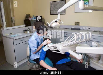 Tragen von Schutzbrillen und Mundmaske Zahnarzt untersucht die Zähne des jungen männlichen Patienten, auch mit besonderen Schutzbrille. Stockfoto